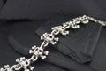 Close-up of a detailed silver bracelet on dark stone.