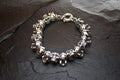 Silver skull charm bracelet on a dark surface.