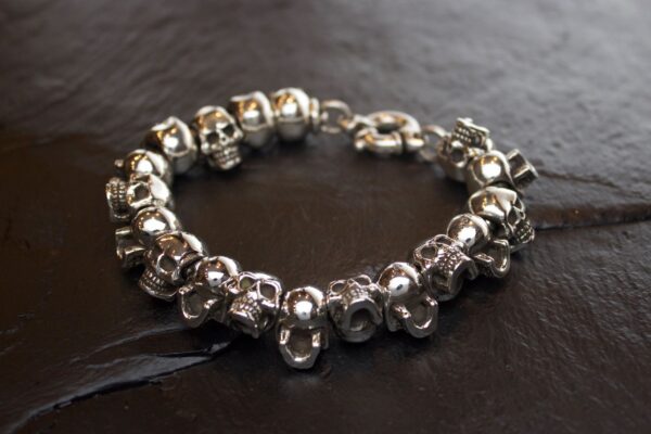 Silver skull bead bracelet on dark surface.