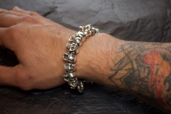 Silver skull bracelet on a tattooed wrist.