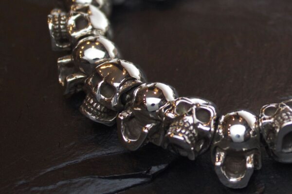 Close-up of a silver skull bracelet on a dark surface.