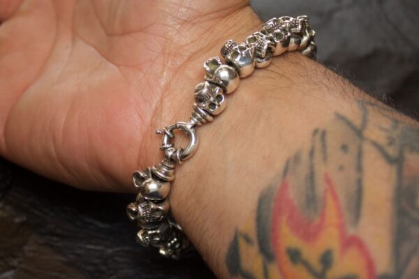 Silver skull bracelet on tattooed wrist.