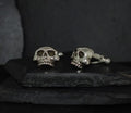 Silver skull cufflinks on a dark surface.