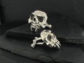 Silver skull-shaped earrings with a dark background.