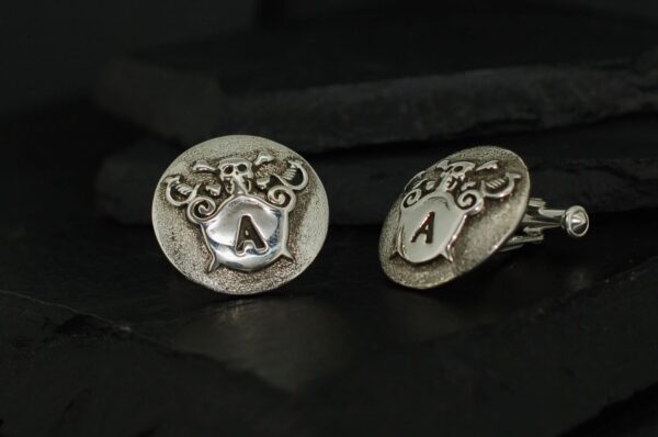 Antique silver cufflinks with intricate patterns and 'A' engraving.