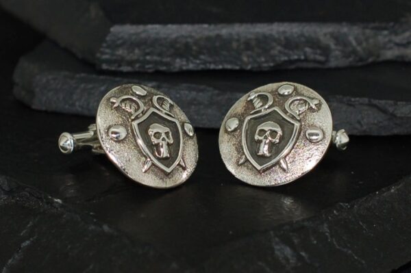 Close-up of silver cufflinks with skull and crossbones design.