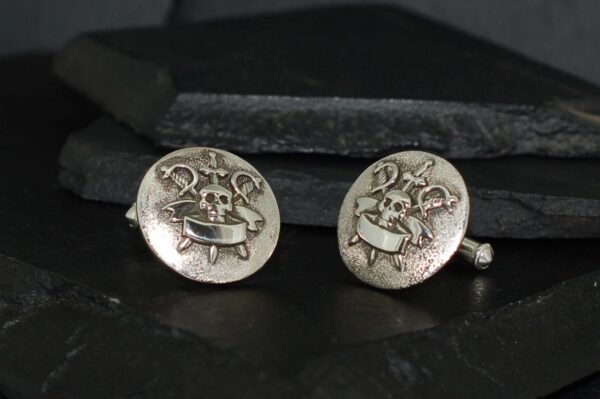 Vintage silver cufflinks with a detailed heraldic crest design.