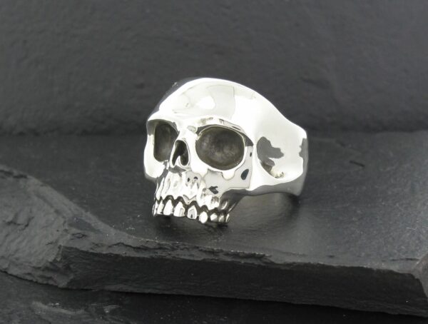 A silver skull-shaped ring on a dark surface.