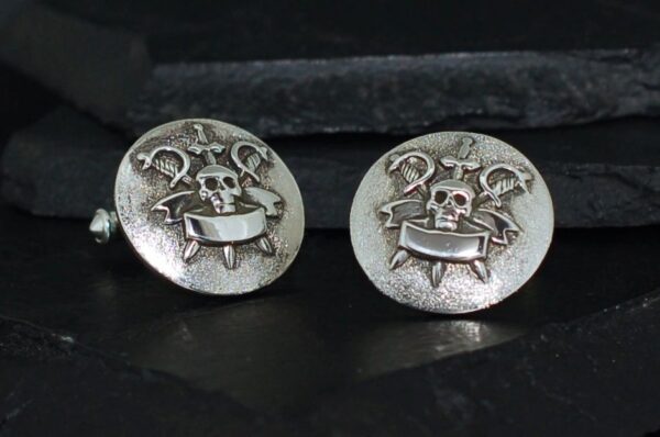 Pair of silver cufflinks with skull and crossbones design.