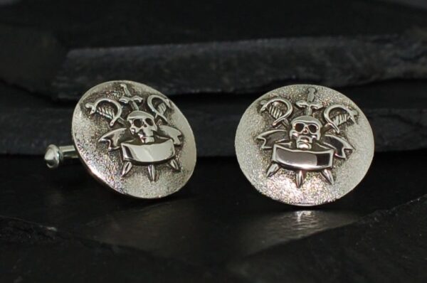 Pair of silver cufflinks with a skull and crown design.