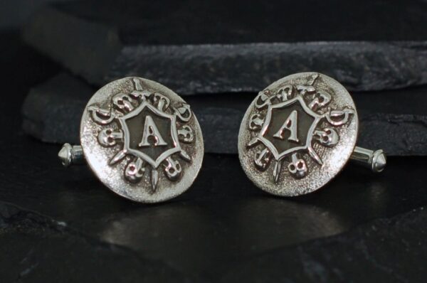 Silver cufflinks with ornate 'A' design and floral motifs.