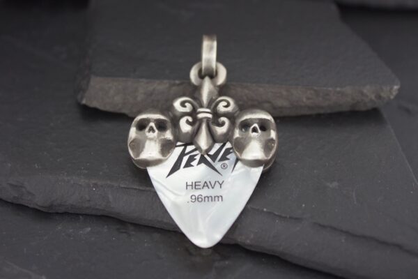 Silver pendant with two skulls and engraved text.