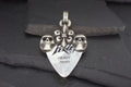 Silver pendant with two skulls and engraved text.