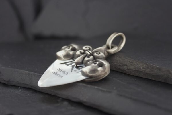 Silver pendant shaped like a spade with intricate heart and scroll designs.
