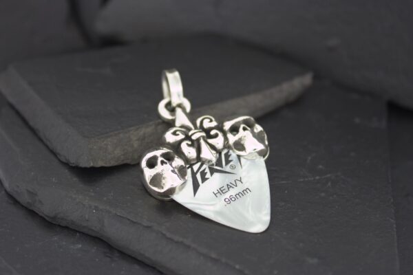 Silver pendant with skull designs and inscription.