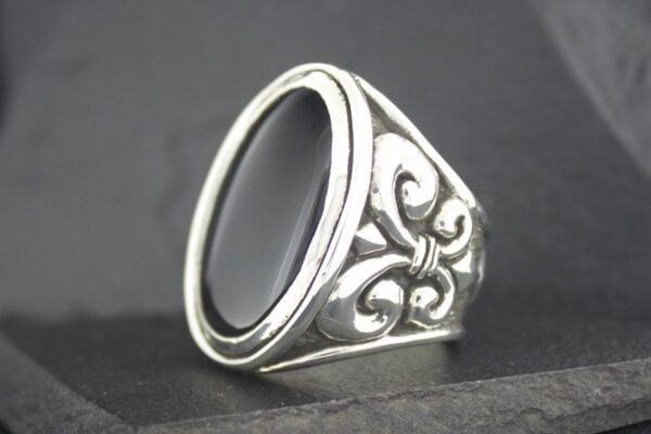 Silver ring with black stone and intricate side design.
