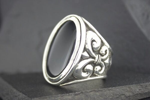 Silver ring with black stone and intricate side design.