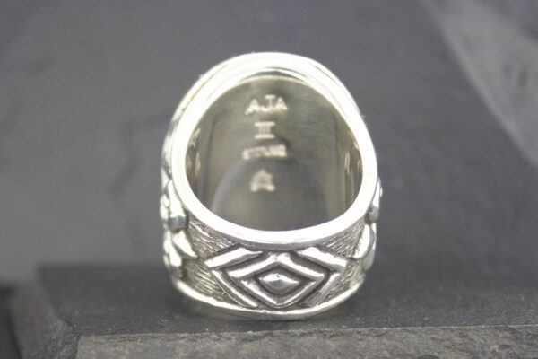 Silver ring with intricate geometric patterns and hallmark stamps inside.
