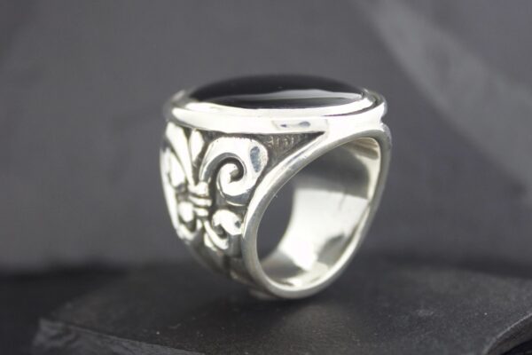 A silver ring with intricate black floral engravings.