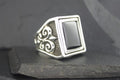 Elegant silver ring with black rectangular stone and intricate side design.