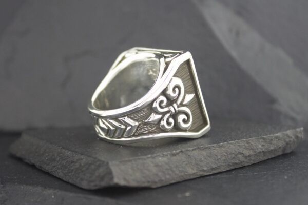 A silver ring with intricate floral and vine engravings.