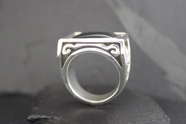 Silver ring with geometric black enamel design.