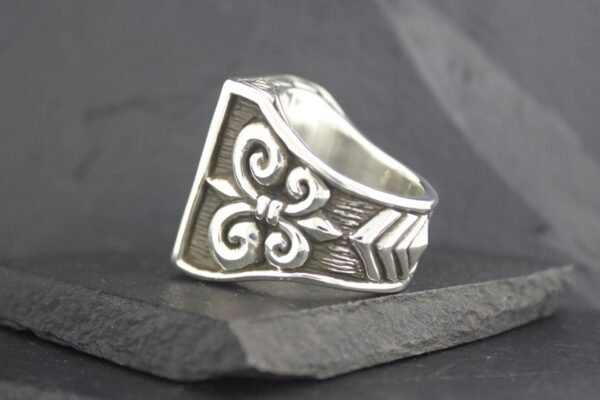 Silver ring with intricate floral and geometric design.