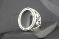 Silver ring with ornate floral design and empty oval bezel.