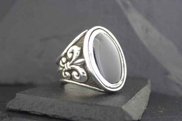 Elegant silver ring with black oval stone and intricate side detailing.