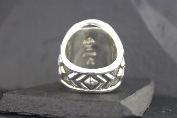 Silver ring with intricate geometric patterns and engraved symbols inside.