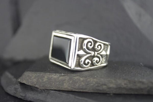 Elegant silver ring with a black square stone and intricate swirl designs.