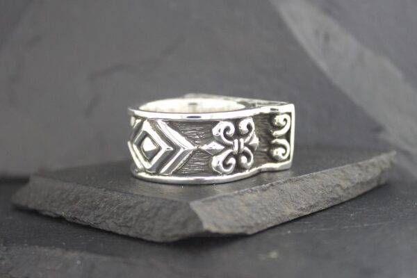 Silver ring with intricate geometric and floral engravings.