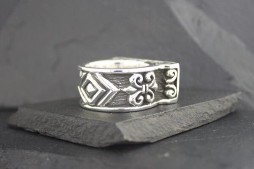 Silver ring with intricate geometric and floral engravings.