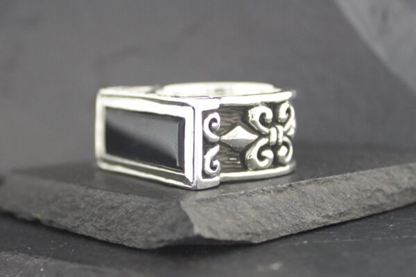 A stylish silver ring with black inlay and decorative side patterns.