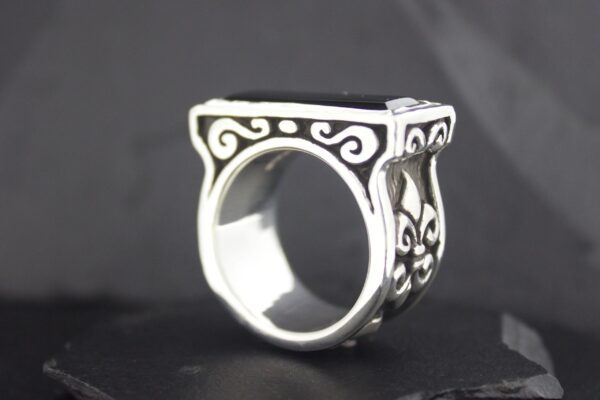 Ornate silver ring with intricate scrollwork design on a square top.