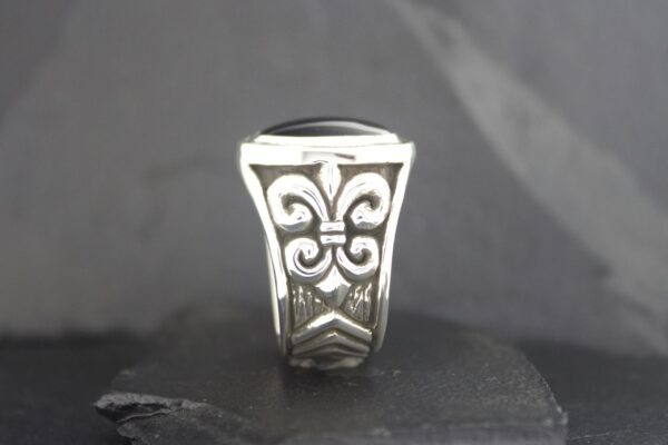 Close-up of an ornate silver ring with intricate floral and swirl designs.