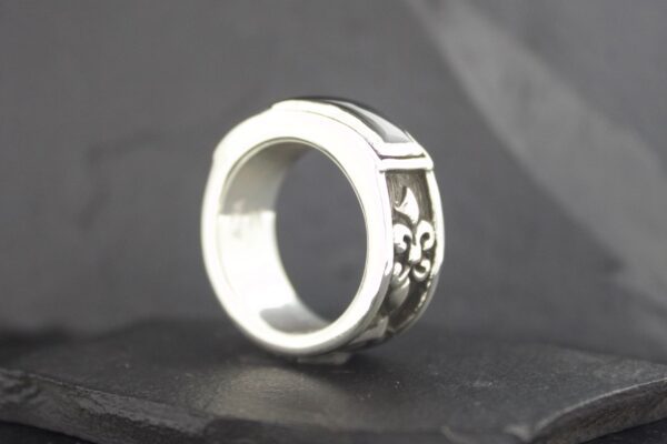 Close-up of a silver ring with intricate floral engravings.