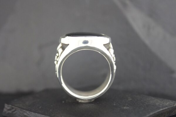 Close-up of a silver ring with black stone details.