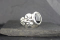 Elegant silver ring with black stone and intricate design.