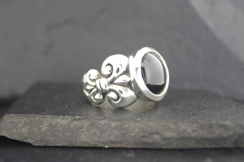 Elegant silver ring with black stone and intricate design.