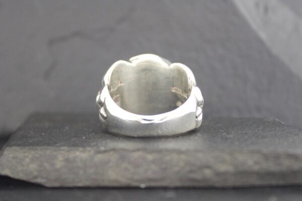 Close-up of a polished silver ring with a smooth, rounded design.