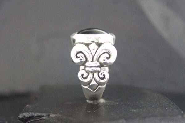 Close-up of a silver ring with intricate, ornamental design.