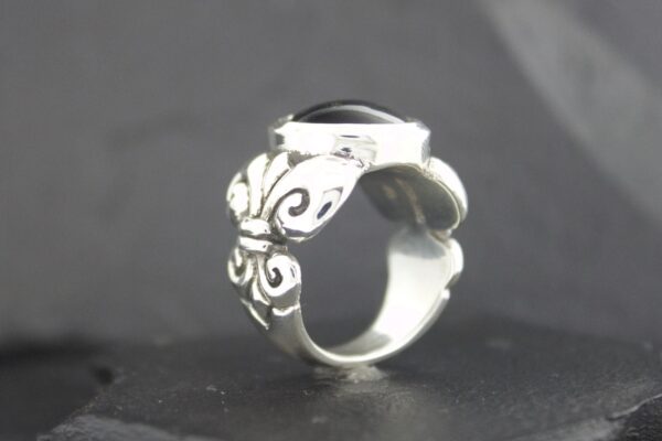 Silver ring with intricate butterfly design on black background.