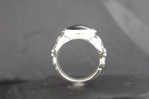 Close-up of a silver ring with an empty setting on a gray background.