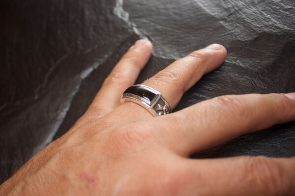 Close-up of a hand wearing a silver and black ring.
