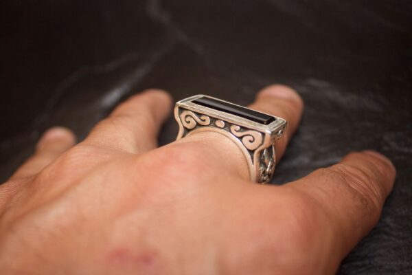 Close-up of a hand wearing an intricately designed silver ring.