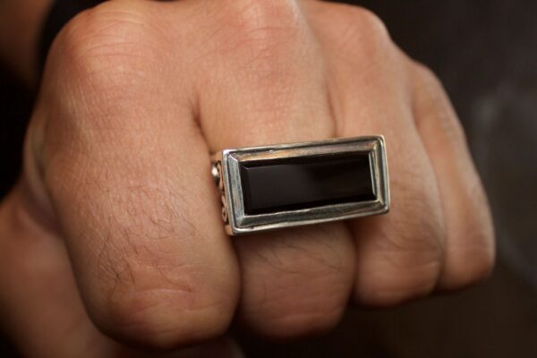 Close-up of a hand wearing a rectangular black stone ring.