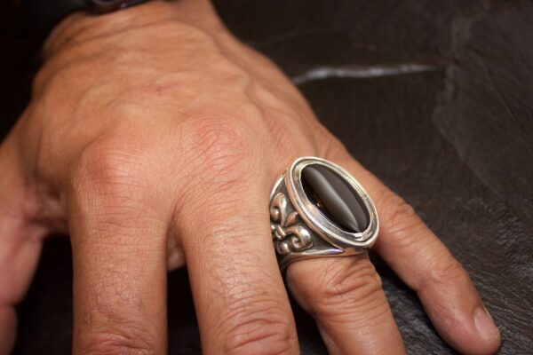 Hand wearing a bold silver ring with a black stone.