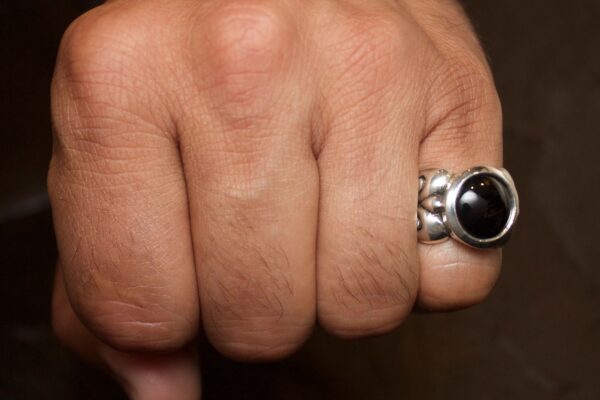 Close-up of a hand with a black stone ring on the finger.