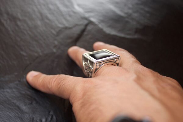 Close-up of a hand wearing a silver ring with a rectangular stone.
